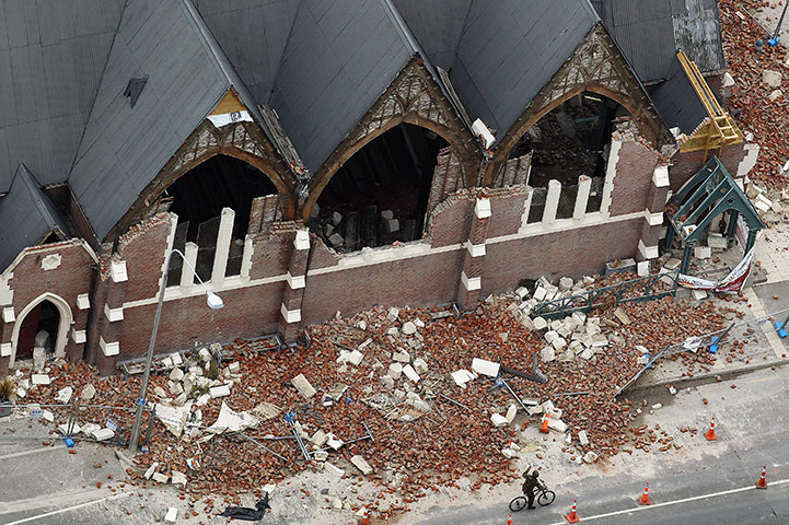 New Zealand aftermath: A man rides past a destroyed church, Christchurch