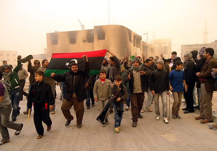 Libya unrest: Libyans hold a flag from the pre-Gaddafi era, during protests in Tobruk