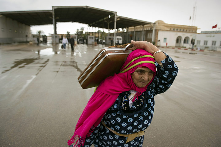 Libya unrest: A Tunisian woman carries her bags past the Rad Jdir border post