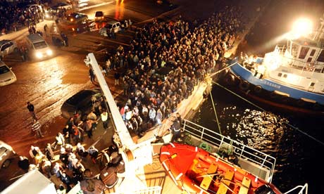 People wait to board a Turkish ferry at the port of Benghazi