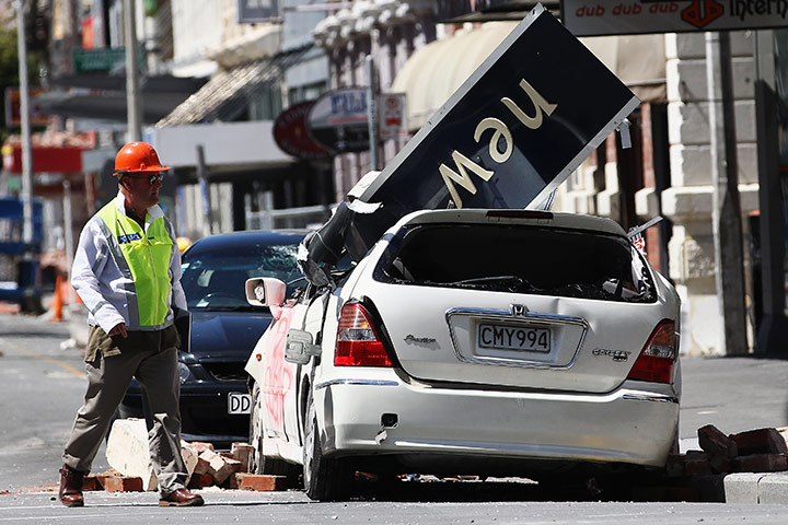 Christchurch earthquake: A rescue worker walks in front of a damaged car in Cathedral Square 