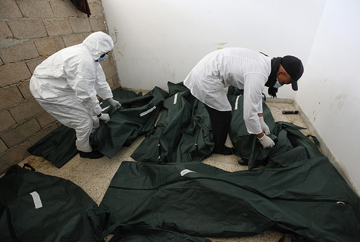 libya: Mortuary assisstants  look at unidentified burned corpses