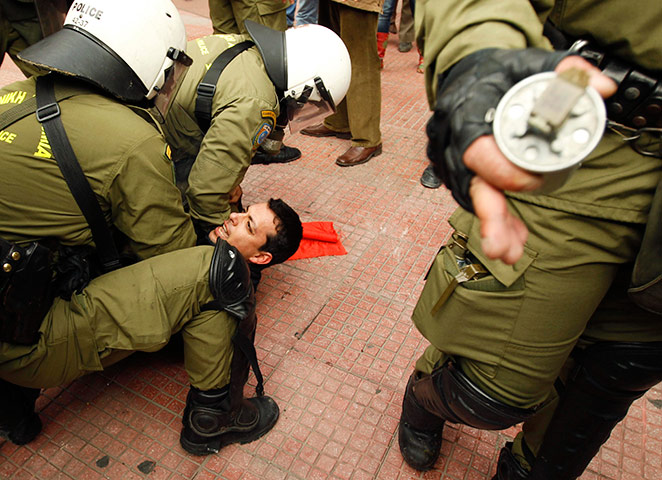 24 hours in pictures: Policemen detain a protester during riots in Athens