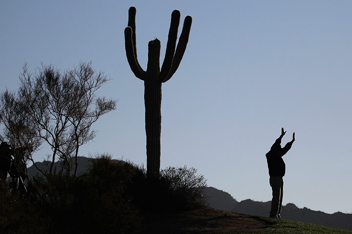 24 hours in pictures: A marshal holds up his hands to quiet spectators as golfers hit