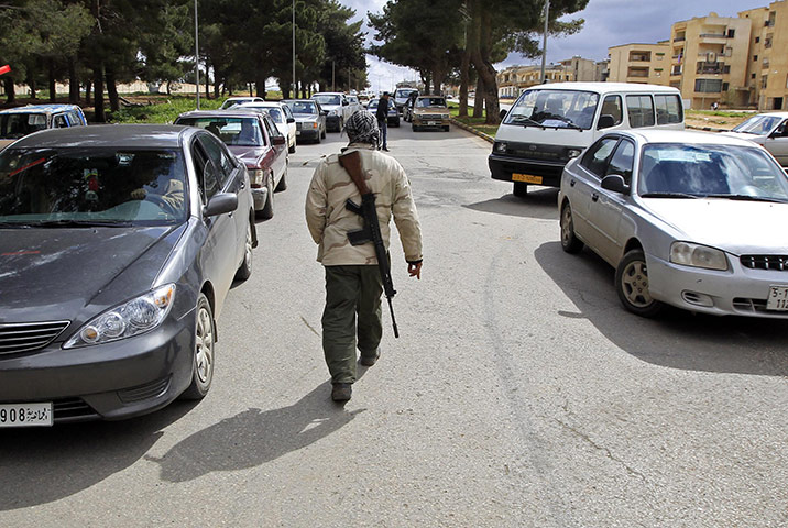 libya : A man walks with a rifle in Shahat