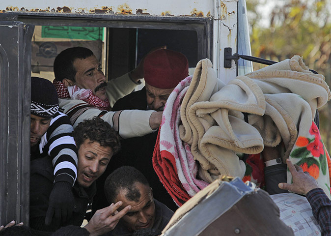Libya 25: Egyptian men who used to work in Libya try to put their luggage into a bus