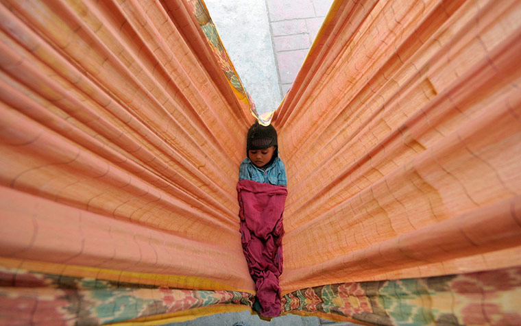 24 hours in pictures: Hyderabad, India: A child of a commuter sleeps in a hammock at a railway station