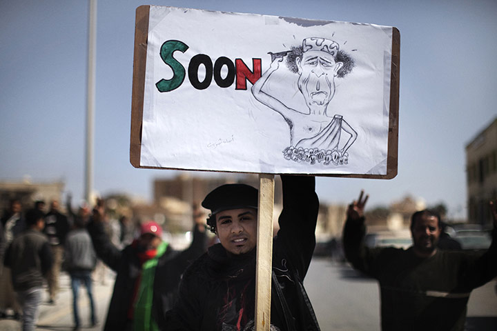 libya update 2: A Libyan demonstrator holds a cartoon de