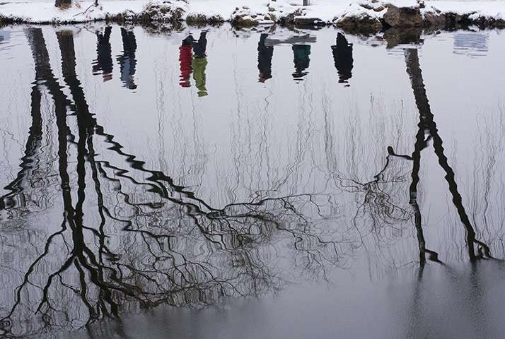 24 hours in pictures: Visitors to a park are reflected in the water of a lake  in beijing