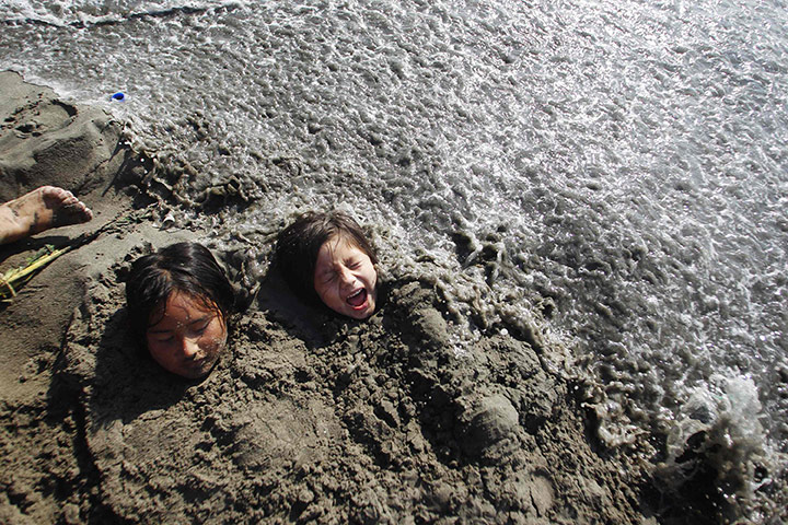 24 hours in pictures: Children buried in the sand at Agua Dulce beach in Lima