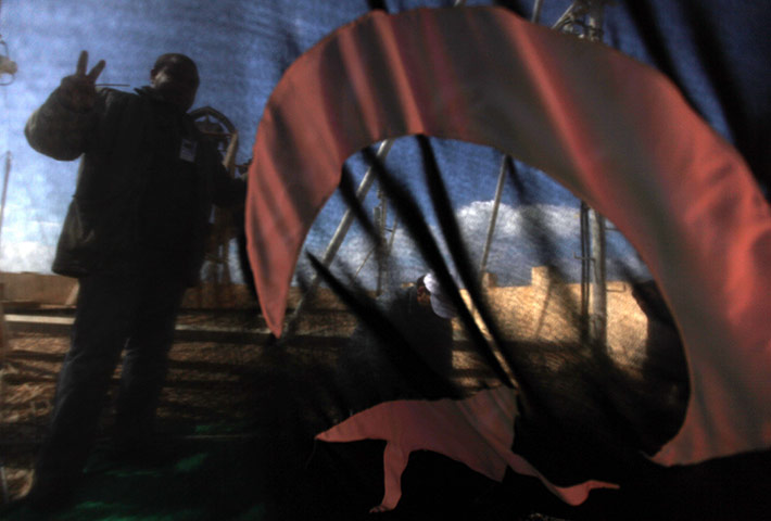 Libya: Anti-government protesters hang the national flag from the rooftop of a hotel in Benghazi 
