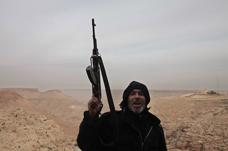 Libya: An anti-government fighter holds his automatic rifle 