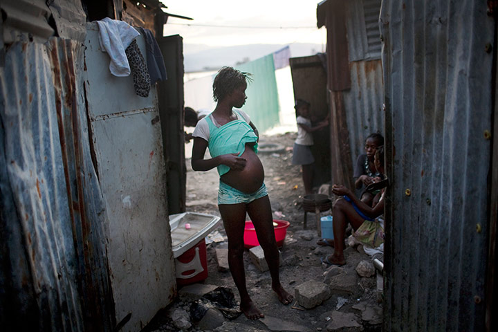24 hours in pictures: A pregnant woman stands in an alleyway in Port-au-Prince,