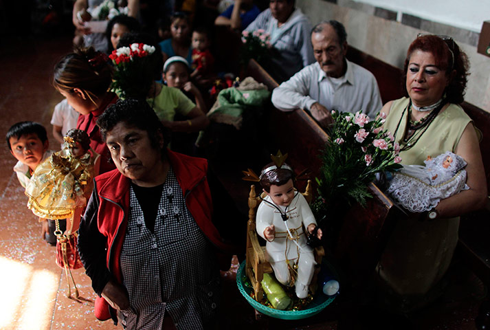 24 hours in pictures: People hold dolls representing baby Jesus during a mass, Mexico City