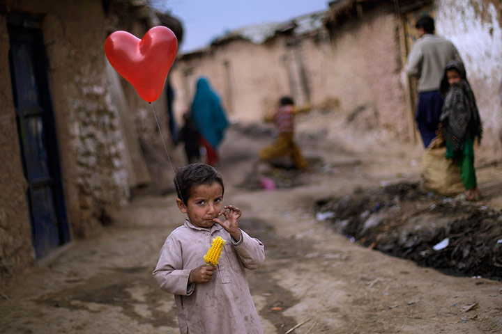 24 hours in pictures: A Pakistani boy holds a balloon while standing  in an alley