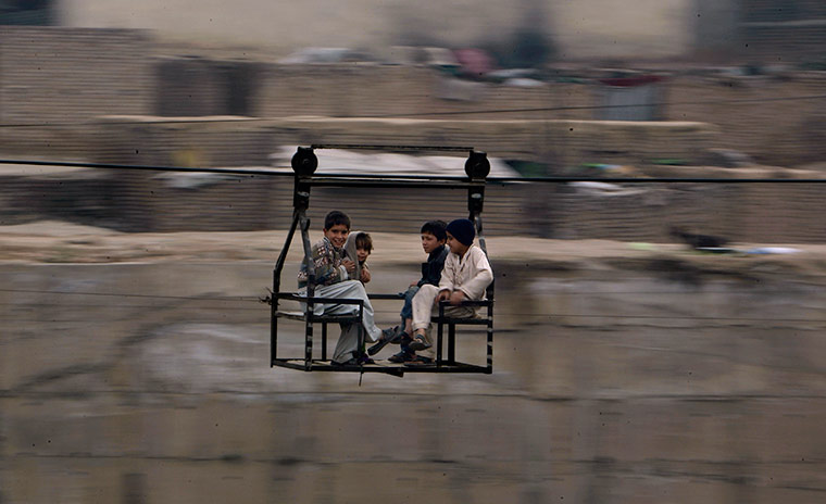 24 hours in pictures: Pakistani children crossing over a stream using an aerial ferry