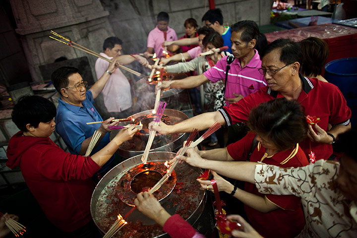 24 hours in pictures: Thai Buddhist gather to light incense and offer prayers at a temple