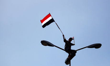 An anti-government protester waves the Yemeni flag from the top of a lamppost in Sana'a