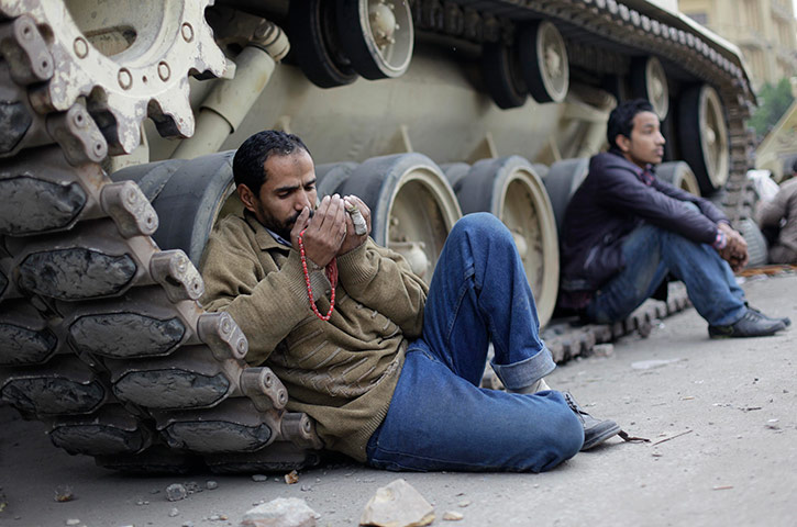 Egypt 05/02: A protestor prays as he leans on a military tank in Tahrir Square, Cairo