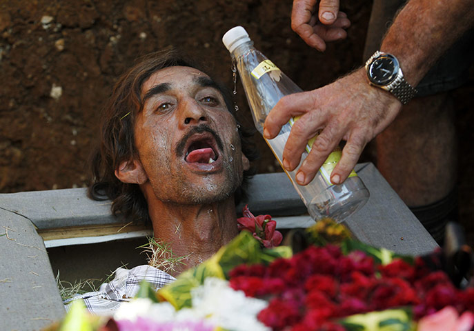 24 hours: Santiago de Las Vegas, Cuba: A man drinks rum while lying in a coffin