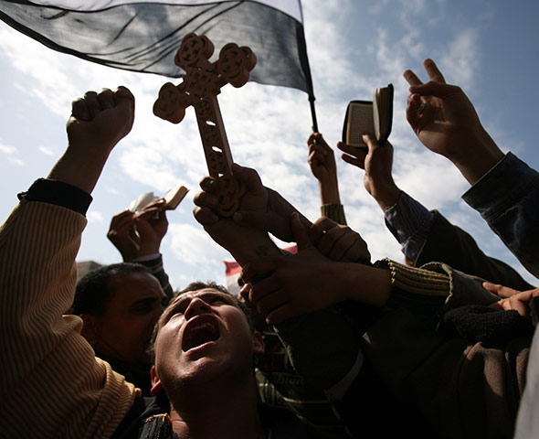 Egypt protests day 13: Protesters hold a Christian coptic cross and copies of the Qur'an