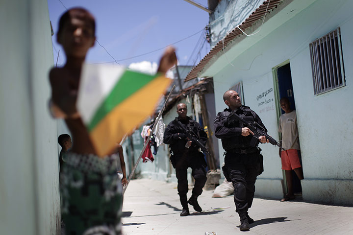 24 hours: Rio de Janeiro, Brazil: A boy plays with a kite as police officers patrol