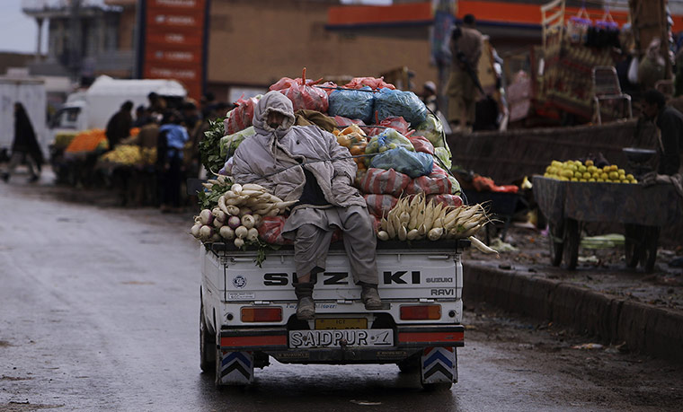 24 hours: Islamabad, Pakistan:A man sits on a vehicle loaded with vegetables 