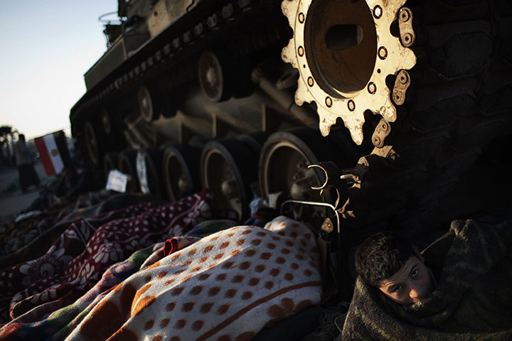Egypt protests day 15: An Egyptian anti-government demonstrator wakes up near an M60 tank