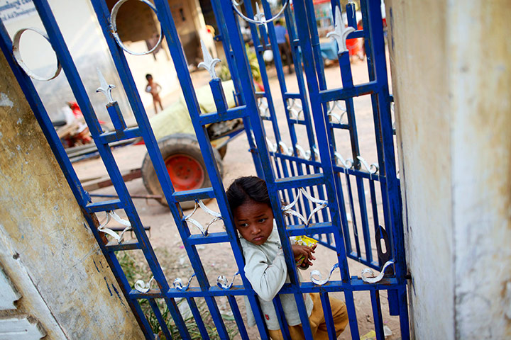 24 hours in pictures: A displaced Cambodian girl looks through the gates of a school