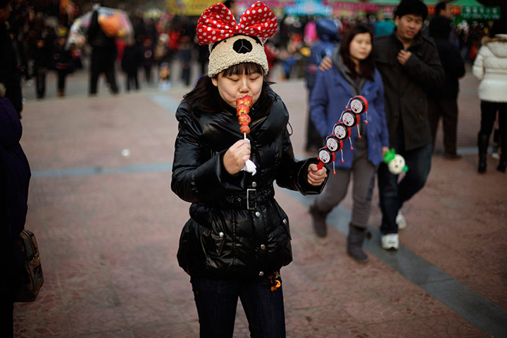 24 hours in pictures: A woman eats candied fruits during Chinese New Year