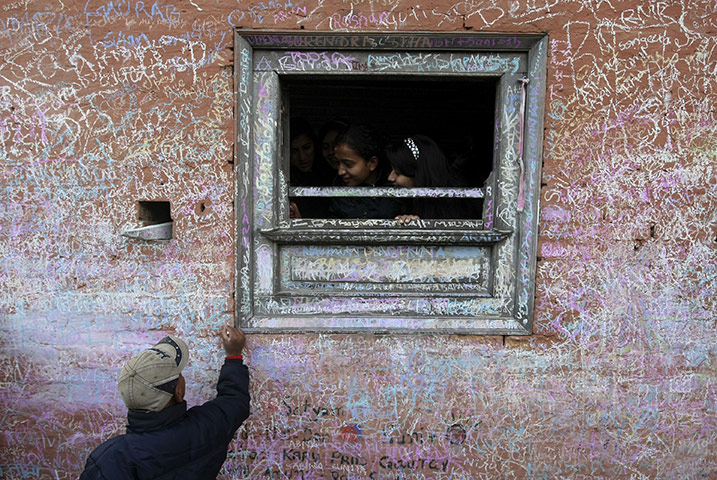 24 hours in pictures: A Nepalese Hindu devotee scribbles messages with chalk on a wall