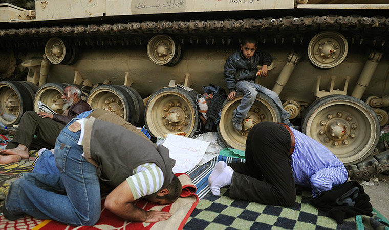 Egypt protests day 15: Protesters pray next to an armoured tank 