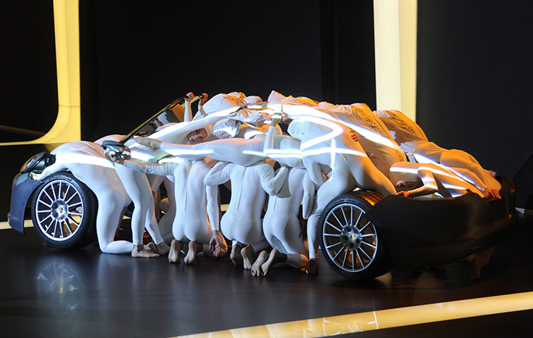 Geneva Motor Show: Acrobats perform to cover a Porche car