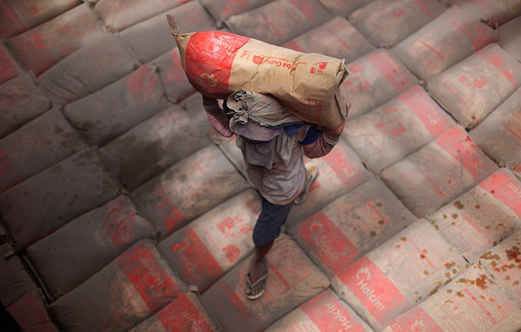 24 hours in pictures: A worker carries a sack of cement inside the hull of a wooden boat, Jakarta