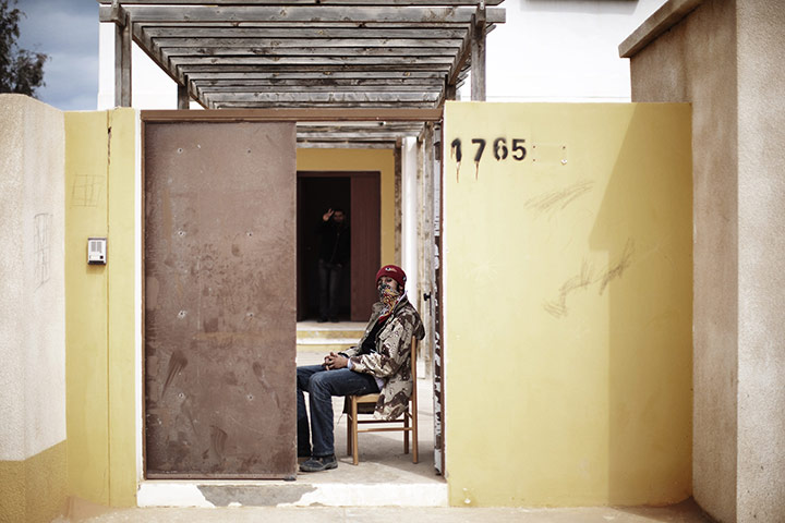 Ras Lanuf battles: A rebel youth sits at the entrance of an apartment block in an alley 