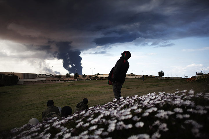 Ras Lanuf battles: Libyan rebels look at a smoke rising from an oil pipe outside Ras Lanuf