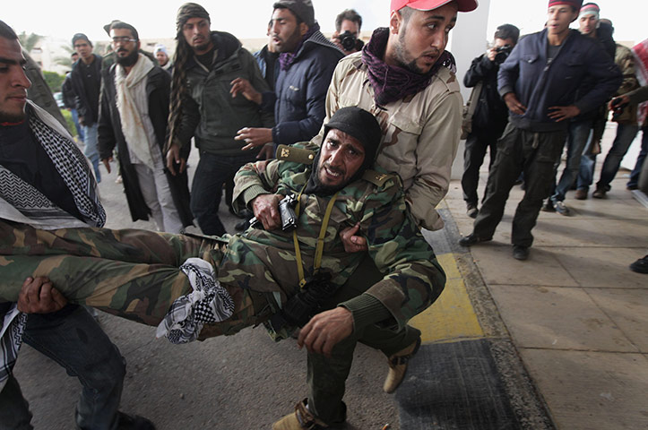 Ras Lanuf battles: A Libyan rebel soldier is carried into a hospital after being injured 