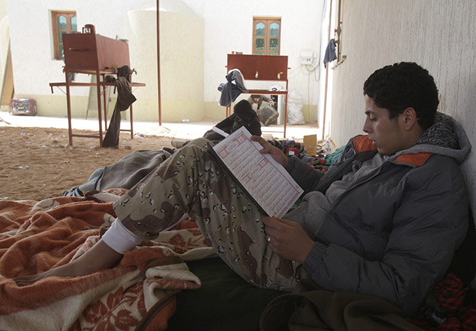 Ras Lanuf Update Libya: An anti-Gaddafi rebel reads the Koran near a checkpoint at Ras Lanuf