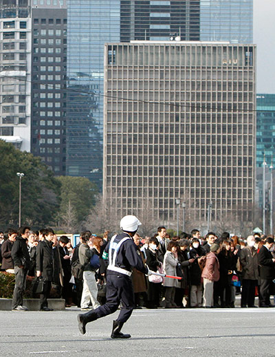 Japan earthquake: A policeman runs across a street after evacuating buildings in Tokyo, Japan