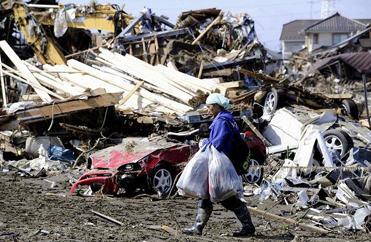 japan quake aftermath: A man walks past buildings destroyed  in Sendai