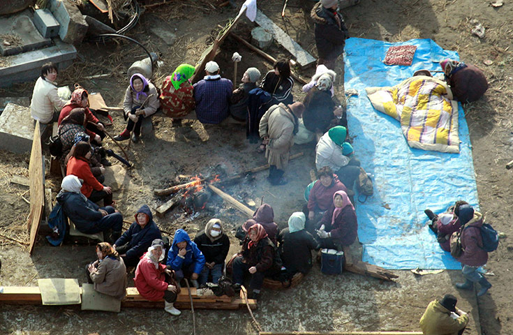 japan disaster aftermath: Survivors in Ishinomaki sit around a fire and wait to be rescued 