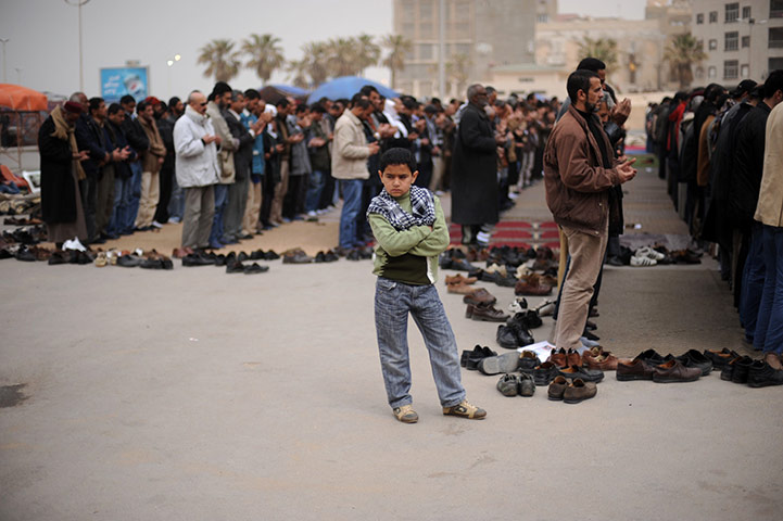 24 hours in pictures: A boy stands next to men praying in benghazi