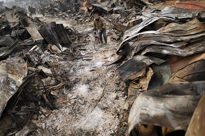 24 hours in pictures: A survivor pushes his bicycle through remains of devastated town of Otsuchi