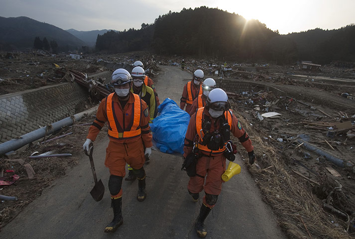 Japan tsunami rescue: Japanese rescue team members carry the body of a man from Saito