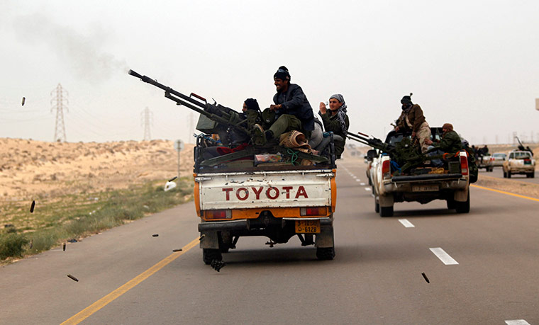 Libya, Ajdabiya: A rebel fires gun as he flees with other rebel fighters from Ajdabiya