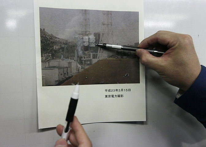 japan disatster: Tokyo Electric Co. employees with a photo of the Fukushima Dai-ichi complex
