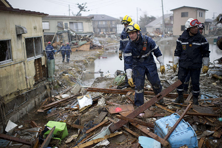 japan disatster: French firemen show the location of a dead body in sendai