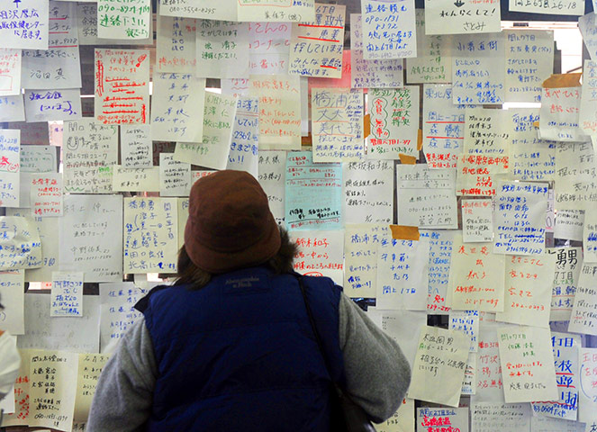 japan disatster: A woman checks notices left for loved ones in Natori 