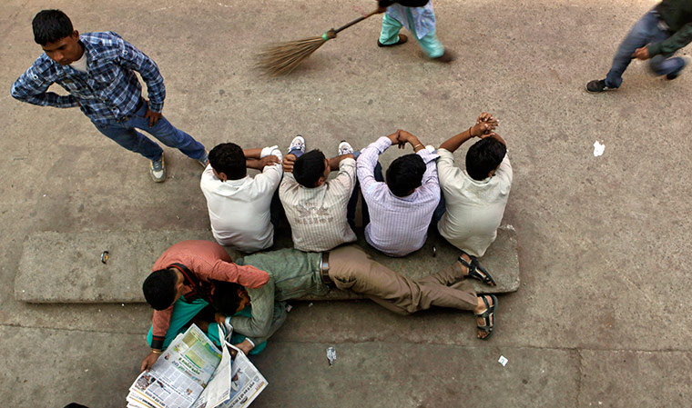 24 hours in pictures: Indian commuters wait for a local passenger train