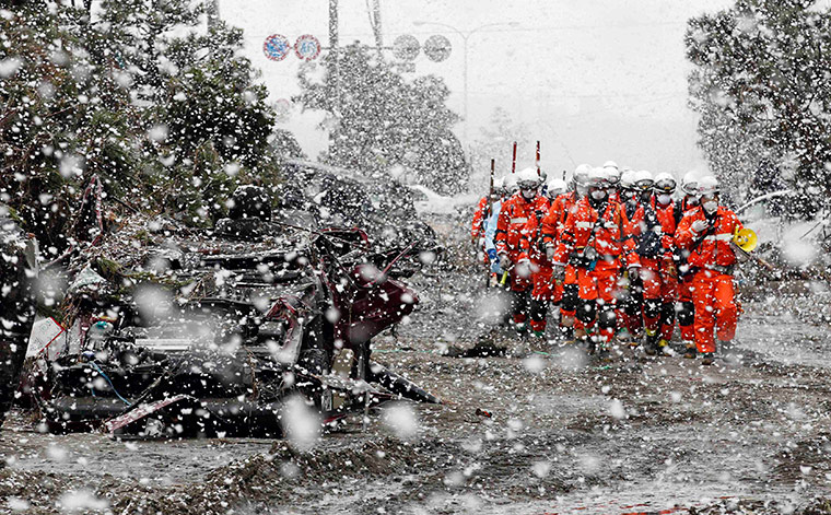 24 hours in pictures: Heavy snow falls on rubble and rescue workers in Sendai, Japan
